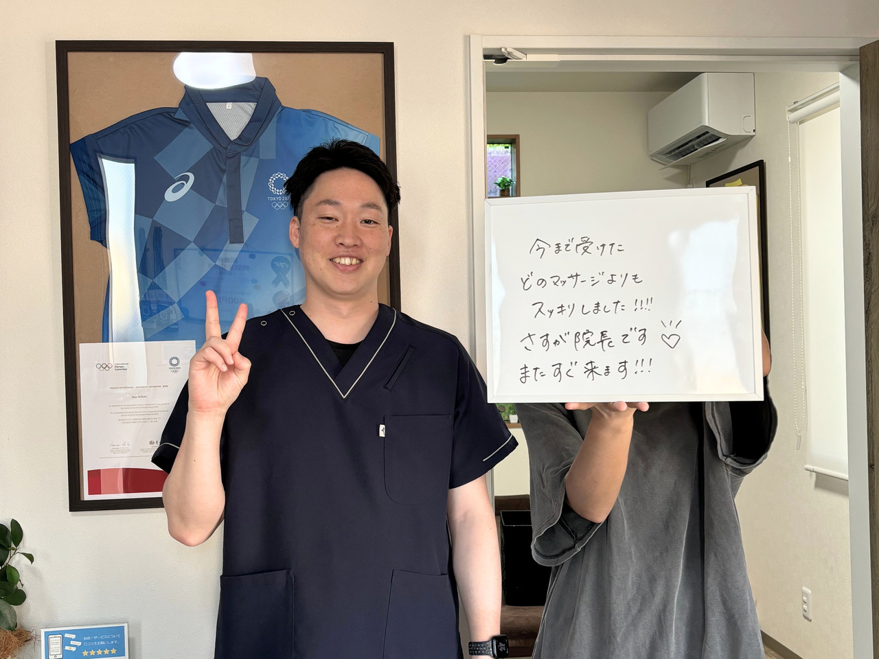 ご感想を書いたボードを持つ来院者の方と院長