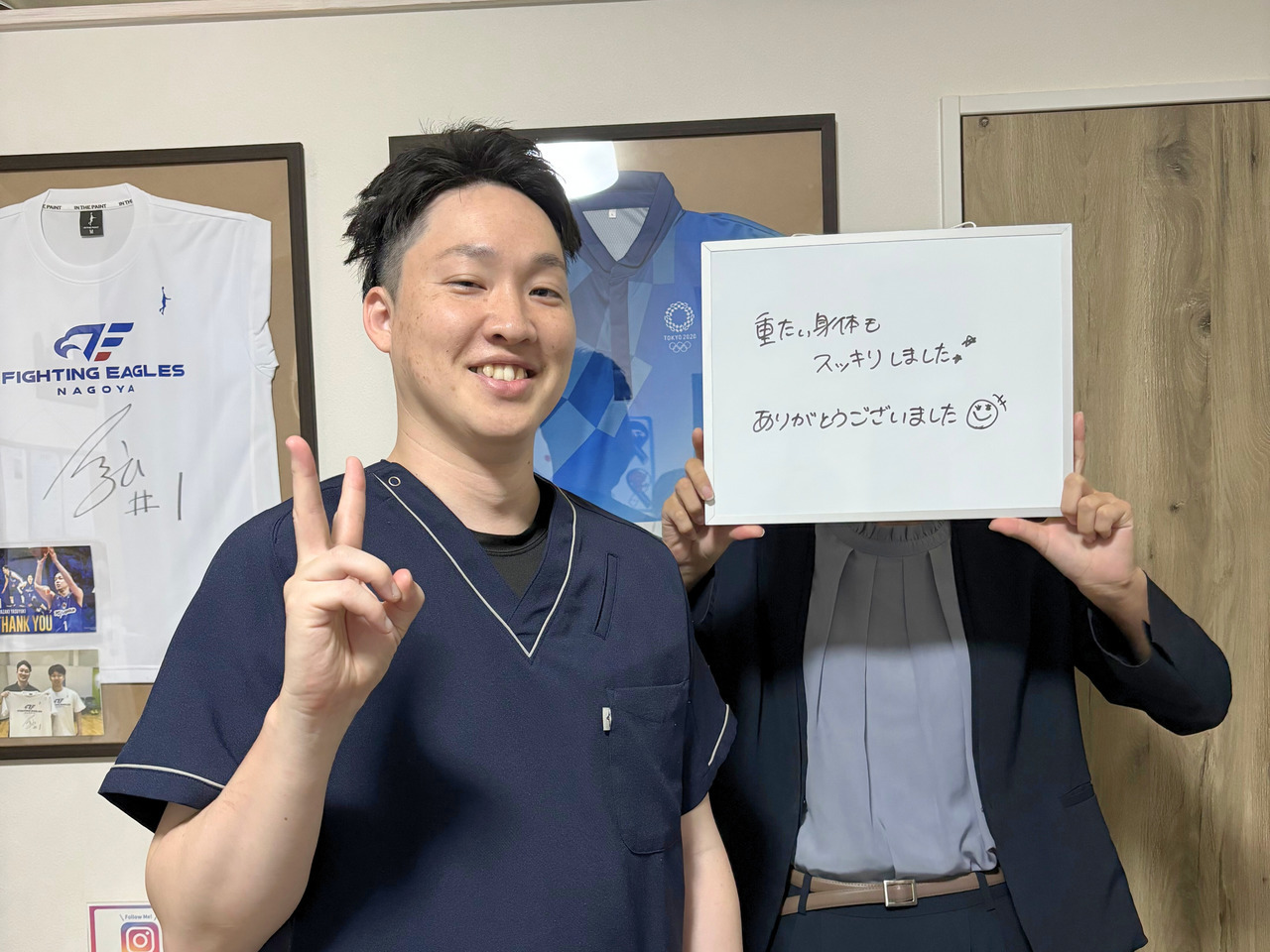 ご感想を書いたボードを持つ来院者の方と院長