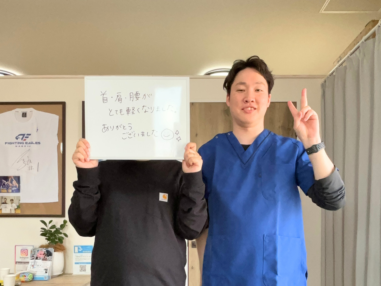 ご感想を書いたボードを持つ来院者の方と院長