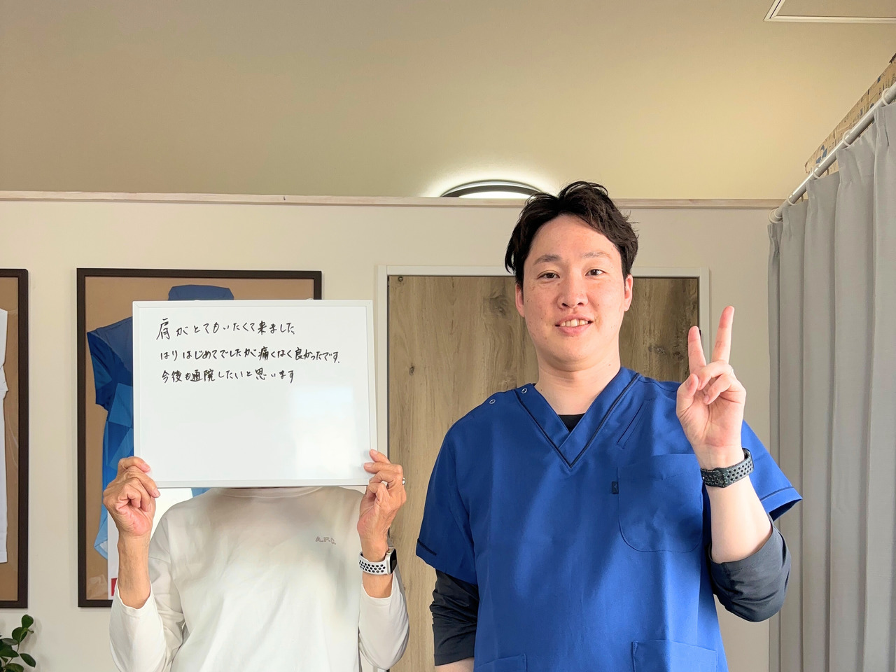 ご感想を書いたボードを持つ来院者の方と院長